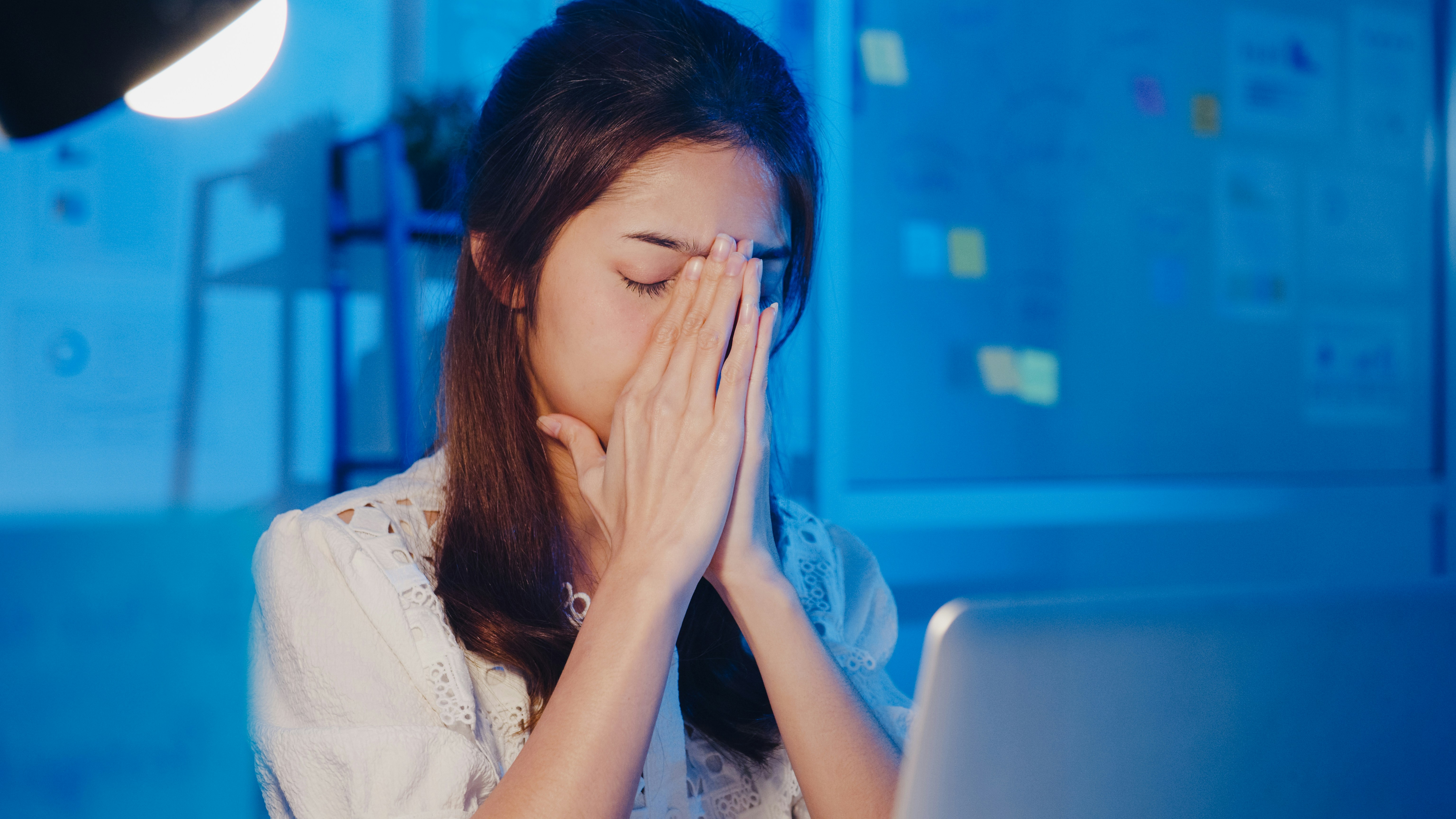 パソコン作業をしている女性が頭痛で悩んでいるイメージ