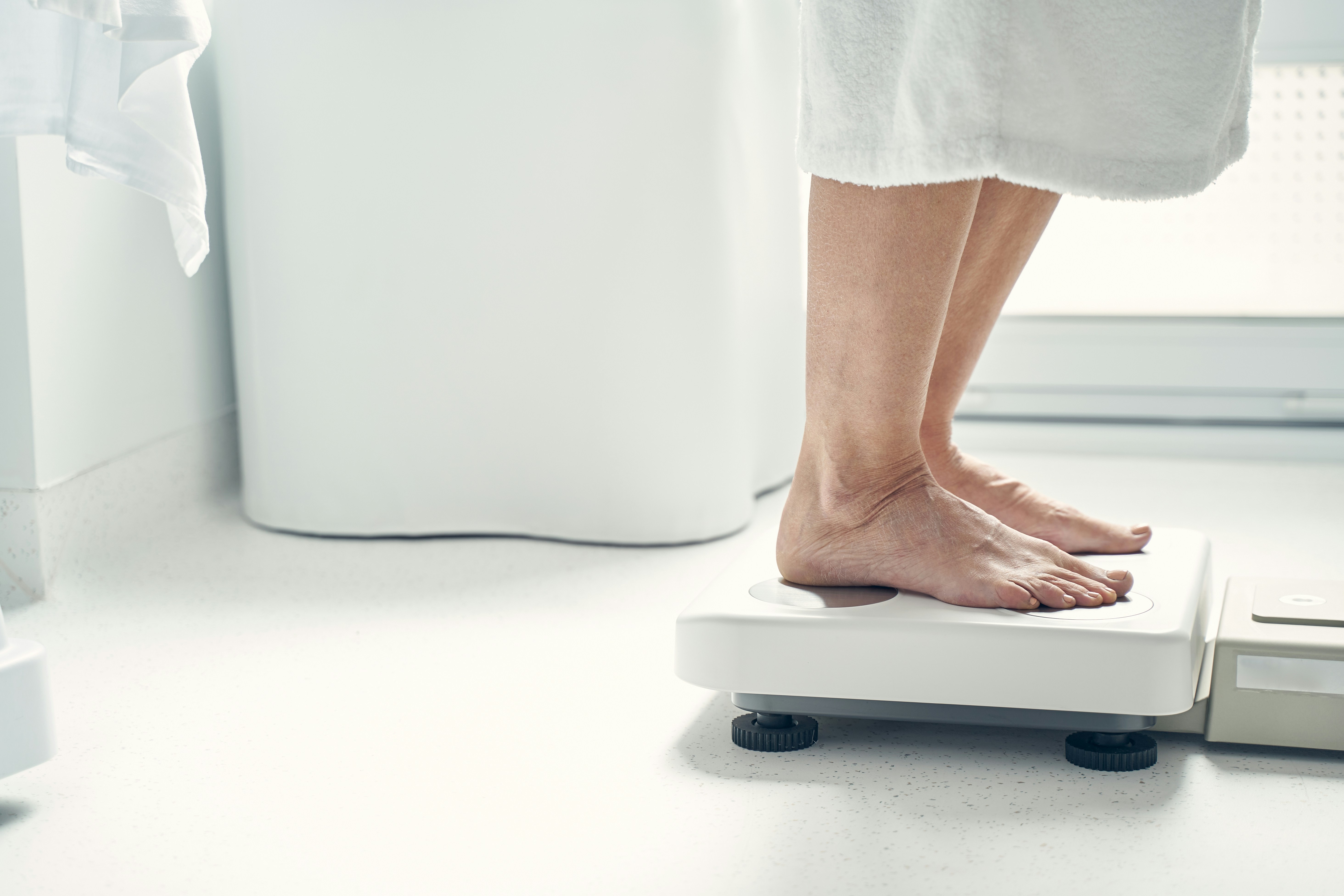 更年期太りに悩んでる女性が体重計に乗っている写真