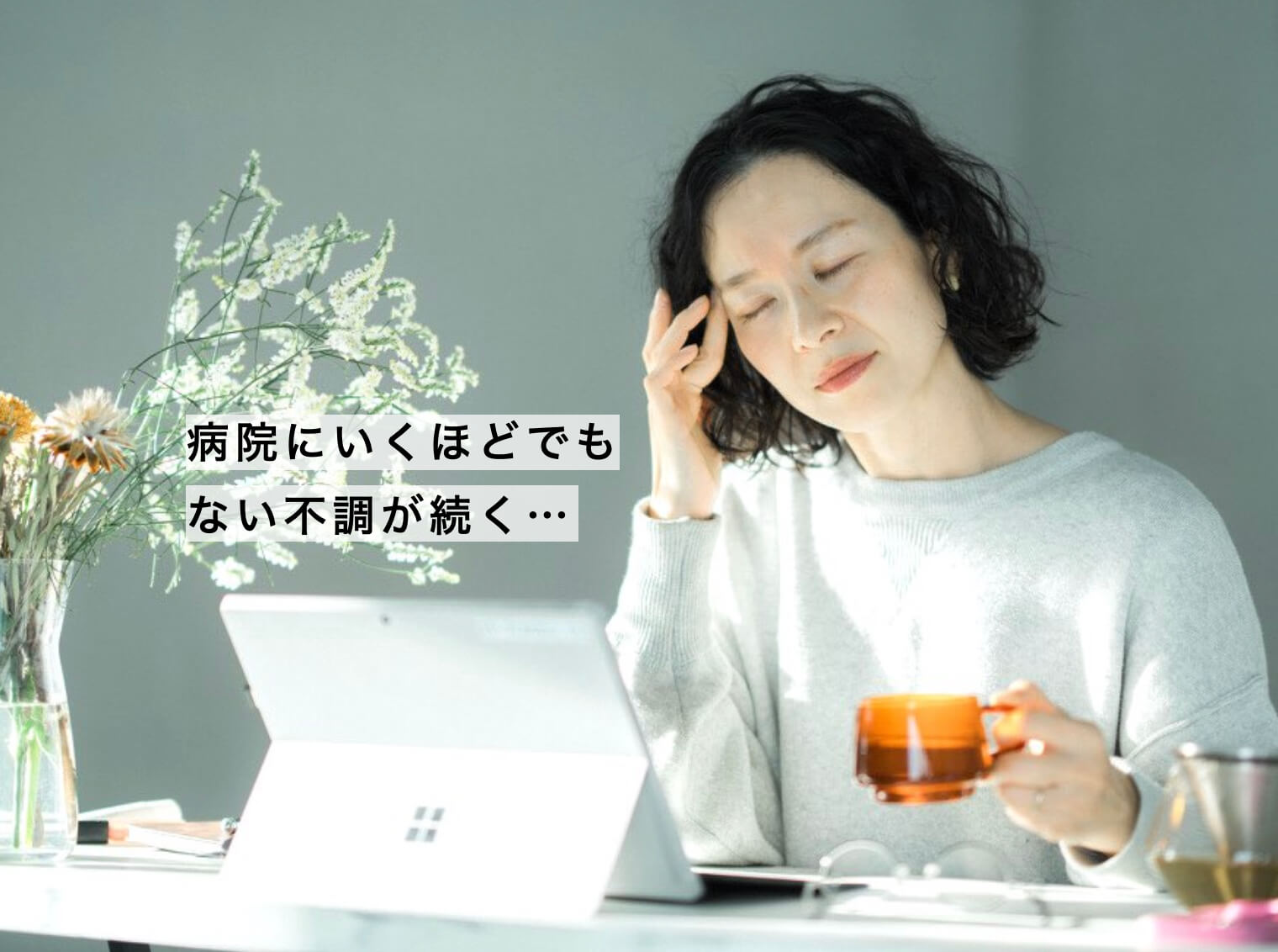 病院にいくほどではないだるさでしんどそうな女性の写真